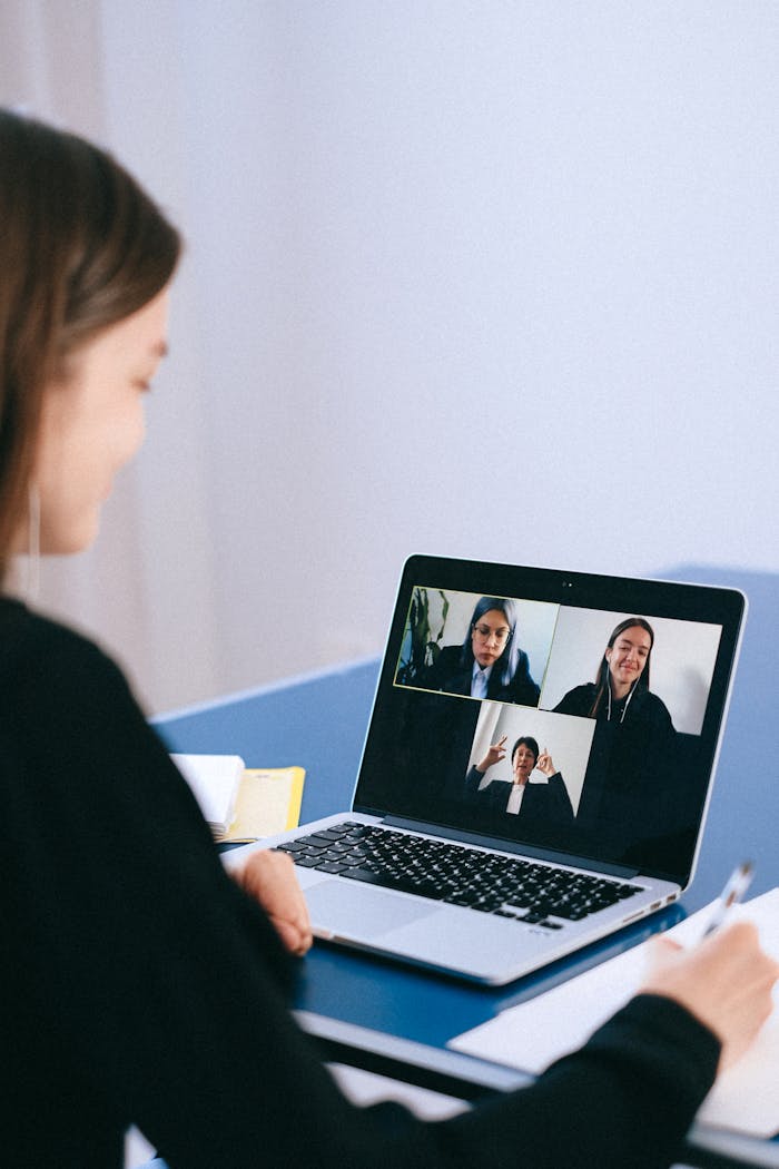 our-story A woman participates in a virtual meeting with colleagues via video call on a laptop.